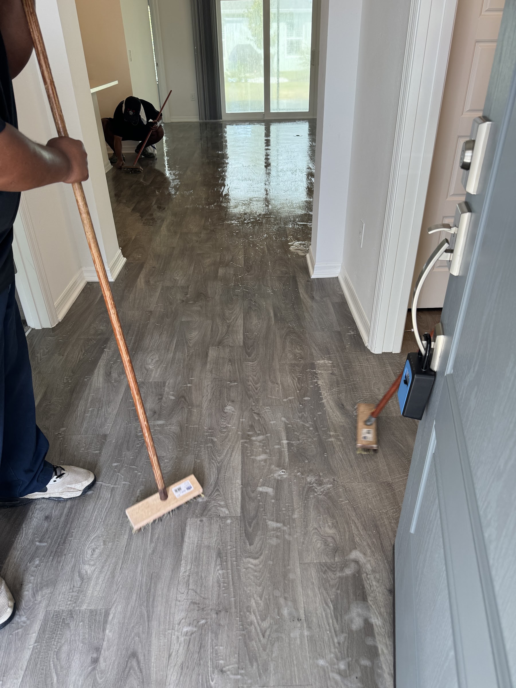Sweeping fresh hardwood floors during post-construction cleanup